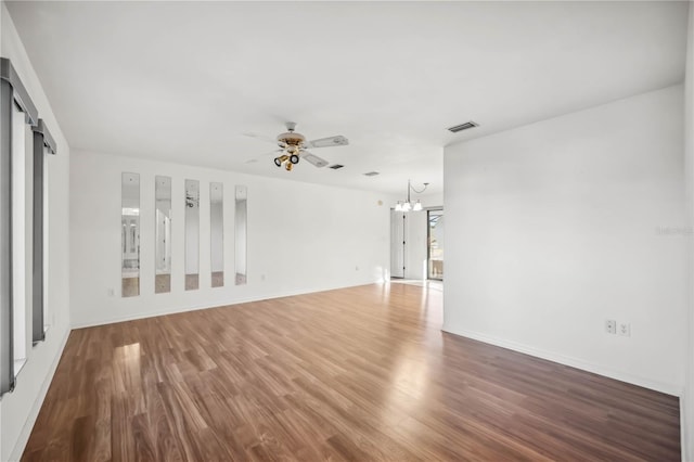 spare room with ceiling fan with notable chandelier and hardwood / wood-style floors