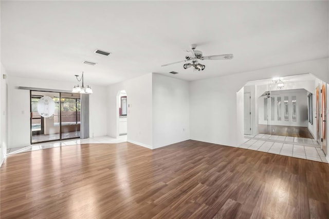 unfurnished living room featuring ceiling fan with notable chandelier and light wood-type flooring