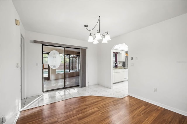 unfurnished dining area with a chandelier, sink, and light hardwood / wood-style flooring