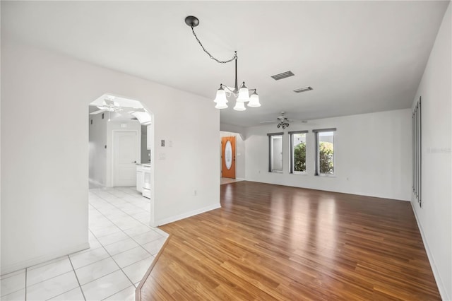 interior space with ceiling fan with notable chandelier and light wood-type flooring