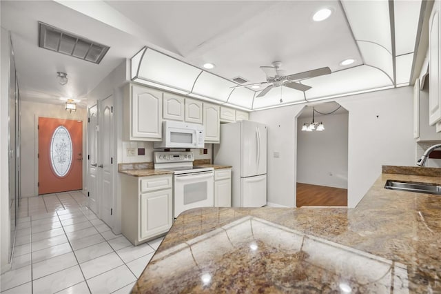 kitchen with sink, white appliances, ceiling fan with notable chandelier, and white cabinets