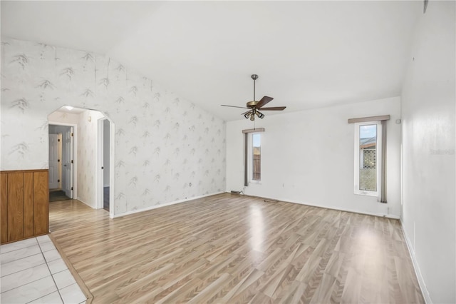 empty room with vaulted ceiling, ceiling fan, and light hardwood / wood-style floors