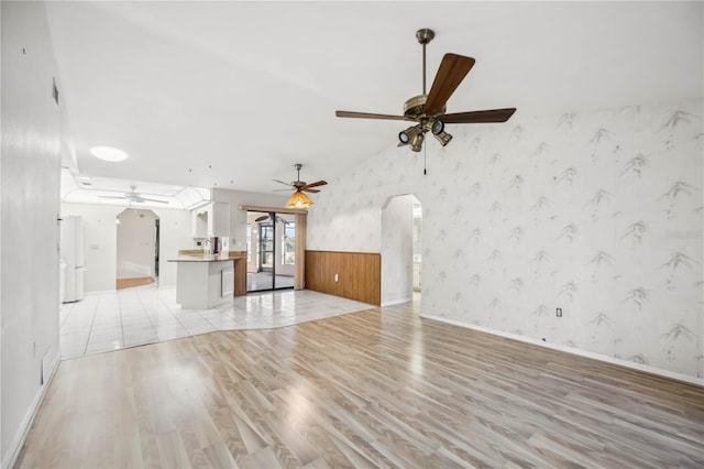 unfurnished living room featuring ceiling fan, lofted ceiling, and light hardwood / wood-style floors