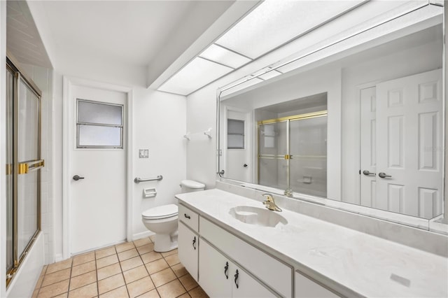 full bathroom with tile patterned flooring, vanity, combined bath / shower with glass door, and toilet