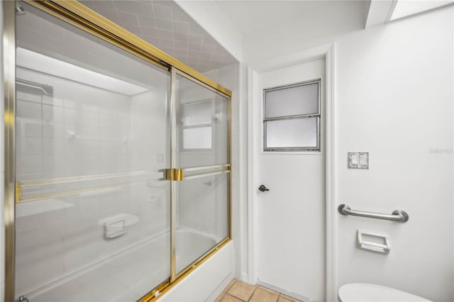 bathroom with toilet, shower / bath combination with glass door, and tile patterned flooring