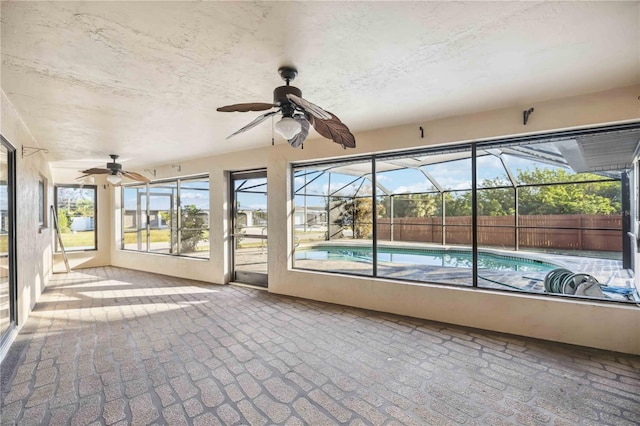 unfurnished sunroom featuring ceiling fan