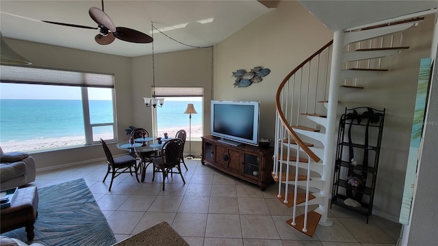 dining space with ceiling fan, light tile patterned floors, and a beach view