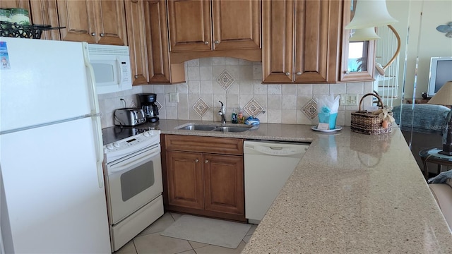 kitchen featuring tasteful backsplash, sink, white appliances, light tile patterned floors, and light stone counters