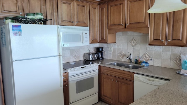 kitchen with light stone countertops, sink, white appliances, and backsplash