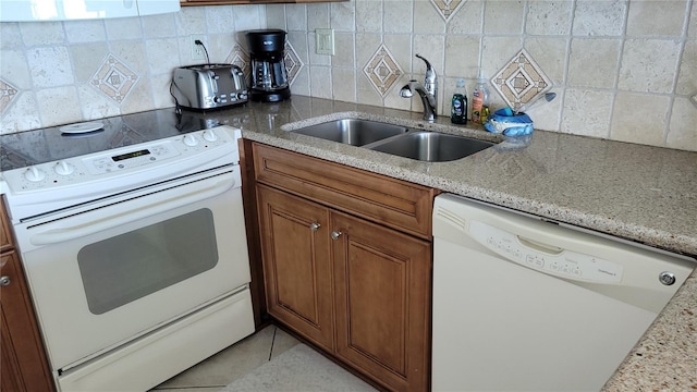 kitchen featuring tasteful backsplash, light stone counters, sink, and white appliances