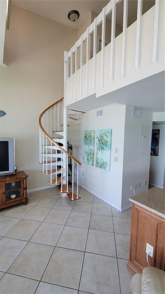 stairs with tile patterned floors and a towering ceiling