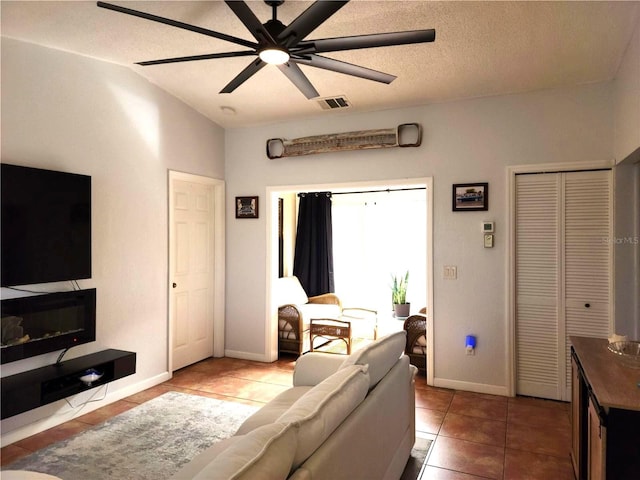 living room with ceiling fan, a textured ceiling, tile patterned floors, and lofted ceiling