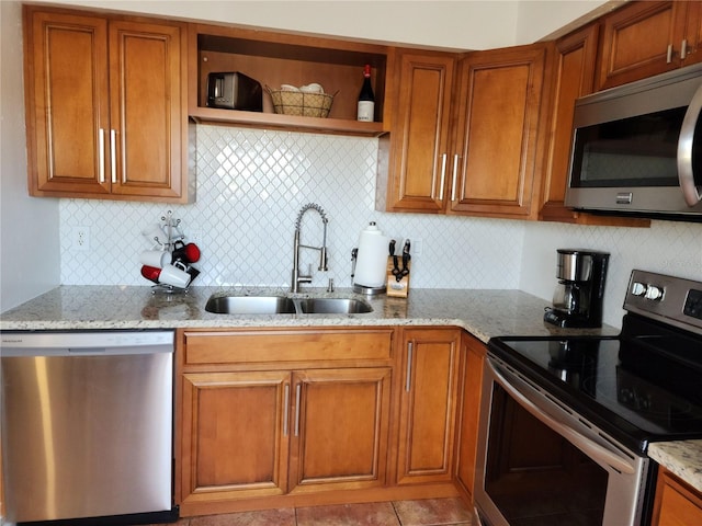 kitchen with backsplash, sink, light tile patterned flooring, light stone countertops, and appliances with stainless steel finishes