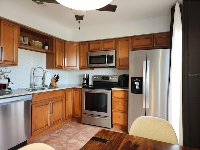 kitchen with light stone countertops, stainless steel appliances, decorative backsplash, sink, and light tile patterned floors