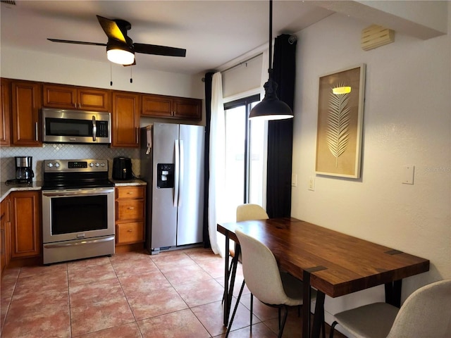 kitchen with pendant lighting, stainless steel appliances, tasteful backsplash, ceiling fan, and light tile patterned floors