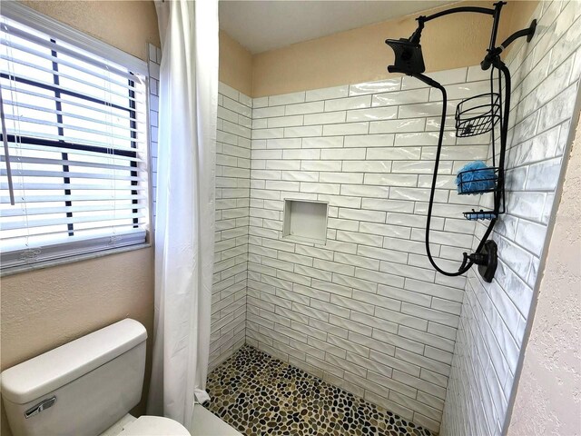 bathroom with curtained shower, toilet, and a healthy amount of sunlight