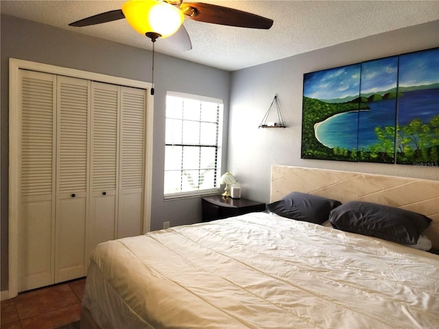 tiled bedroom featuring a textured ceiling, ceiling fan, and a closet