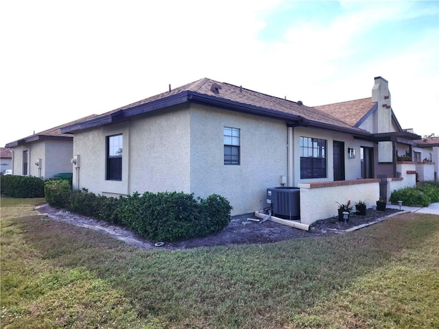 view of property exterior with central air condition unit and a yard