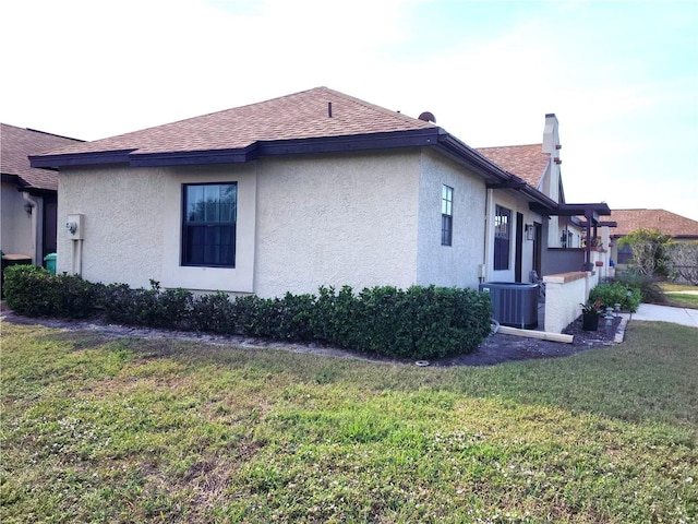 view of side of home with central AC and a lawn