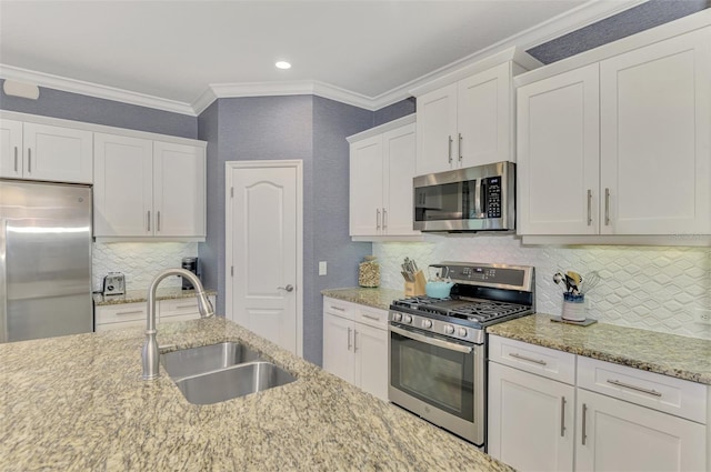 kitchen featuring white cabinets, stainless steel appliances, decorative backsplash, sink, and ornamental molding