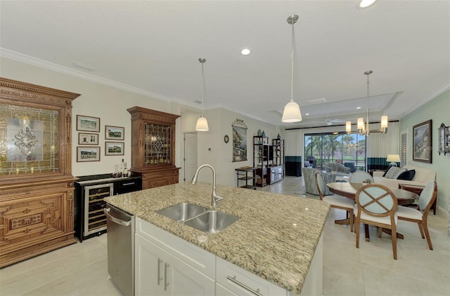 kitchen featuring white cabinetry, a center island with sink, light stone countertops, pendant lighting, and sink