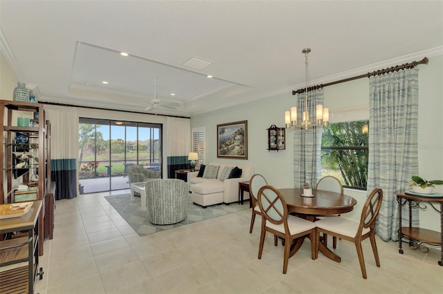 dining space featuring ceiling fan with notable chandelier, ornamental molding, and a raised ceiling