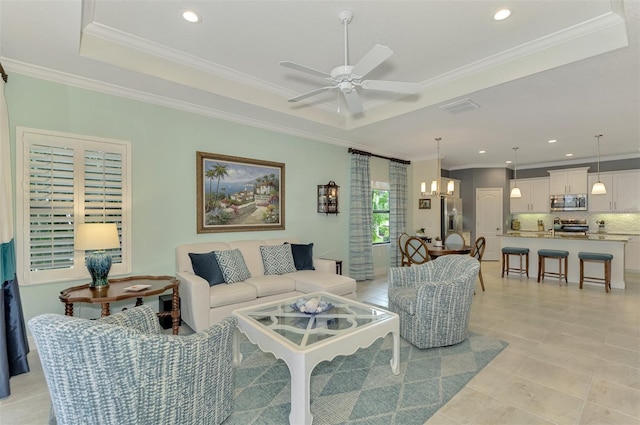 tiled living room featuring ceiling fan with notable chandelier, ornamental molding, and a raised ceiling