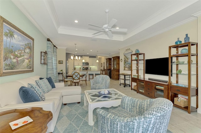 tiled living room with a raised ceiling, ceiling fan with notable chandelier, and ornamental molding