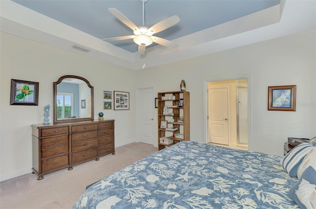 carpeted bedroom featuring ceiling fan and a tray ceiling