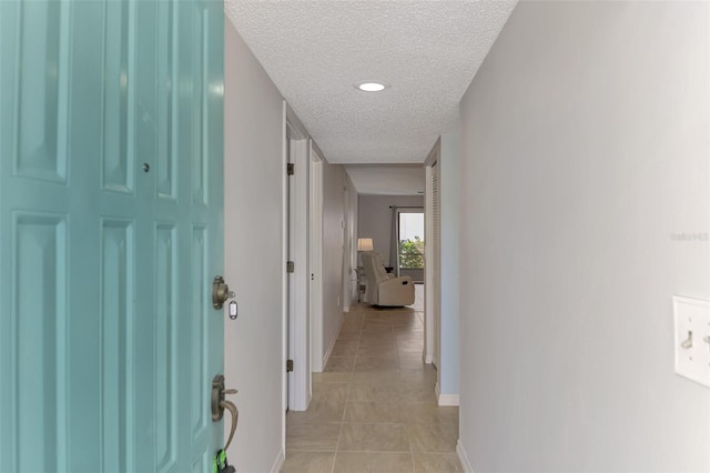 hallway with light tile patterned floors and a textured ceiling