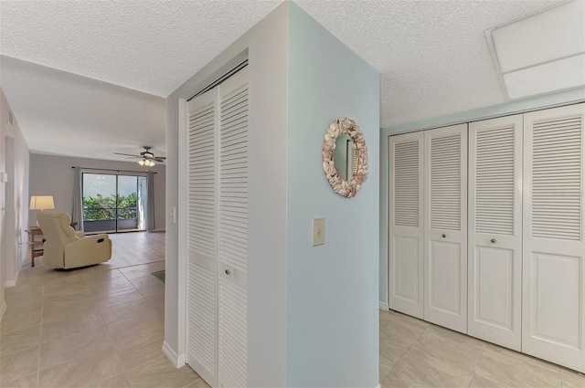 hallway with a textured ceiling and light tile patterned floors