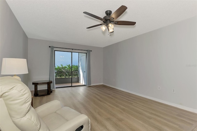 unfurnished living room featuring ceiling fan, light hardwood / wood-style floors, and a textured ceiling