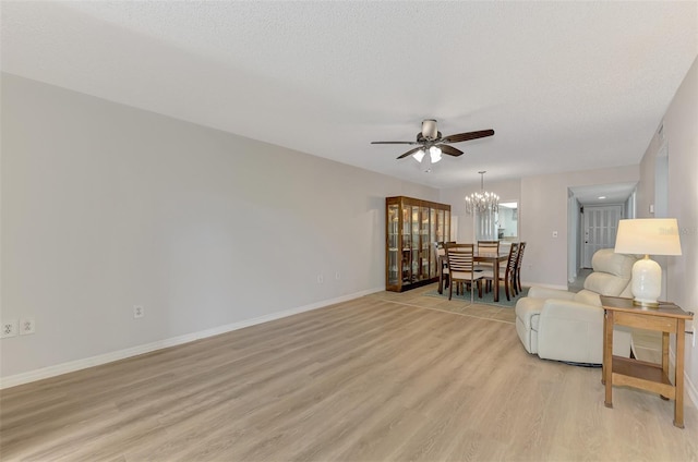 living room with ceiling fan with notable chandelier, a textured ceiling, and light hardwood / wood-style flooring