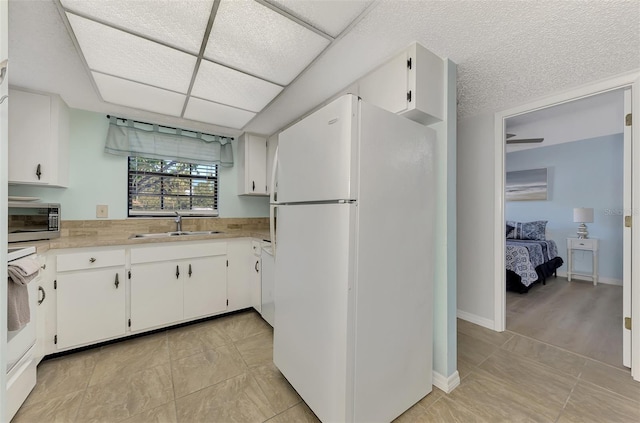 kitchen featuring white cabinetry, white fridge, sink, and light tile patterned floors