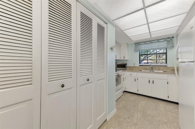 kitchen with white cabinetry, white appliances, and sink