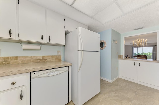 kitchen with pendant lighting, white appliances, a chandelier, and white cabinets