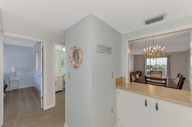 hallway with a chandelier and a textured ceiling