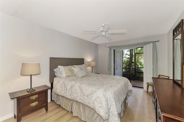 bedroom featuring access to exterior, light hardwood / wood-style floors, and a textured ceiling