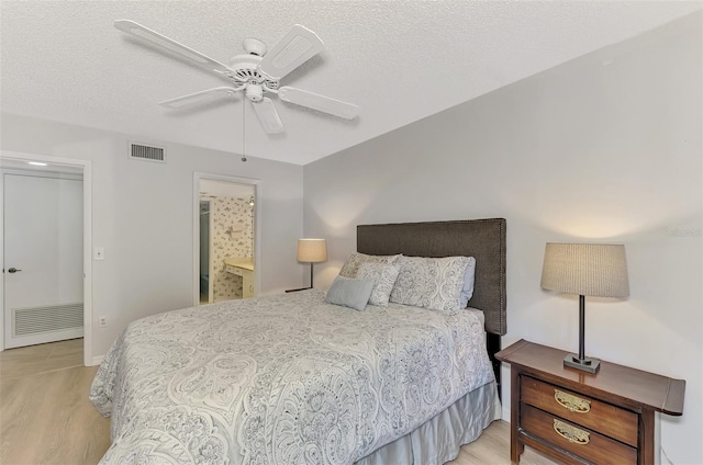 bedroom with ceiling fan, light hardwood / wood-style floors, a textured ceiling, and ensuite bathroom