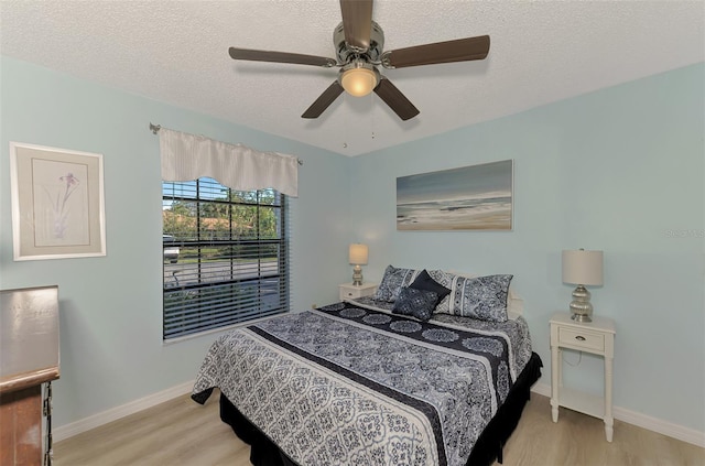 bedroom with ceiling fan, a textured ceiling, and light hardwood / wood-style floors