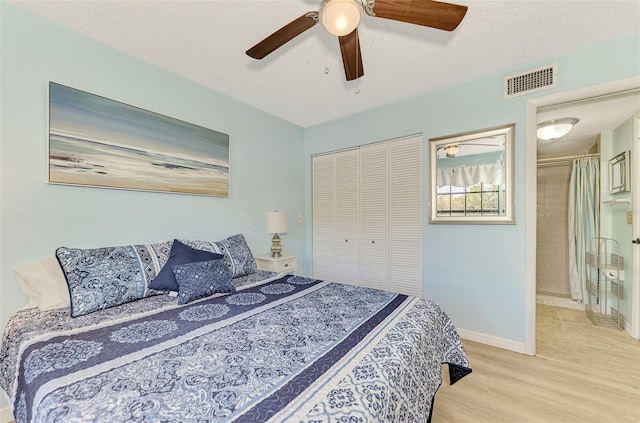 bedroom with ensuite bath, a textured ceiling, light hardwood / wood-style flooring, a closet, and ceiling fan