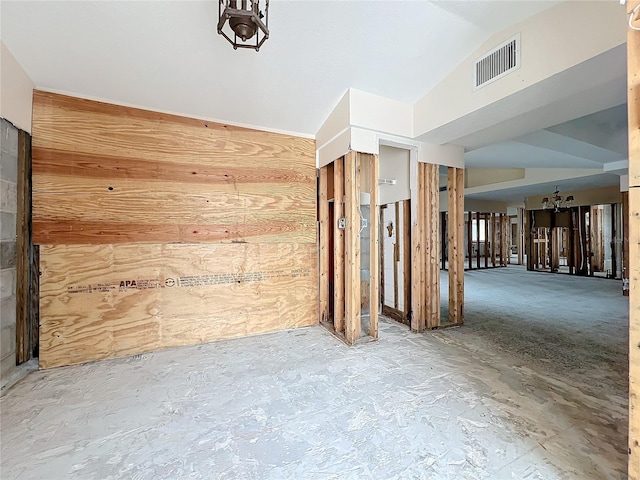 unfurnished room with wood walls, concrete flooring, and lofted ceiling