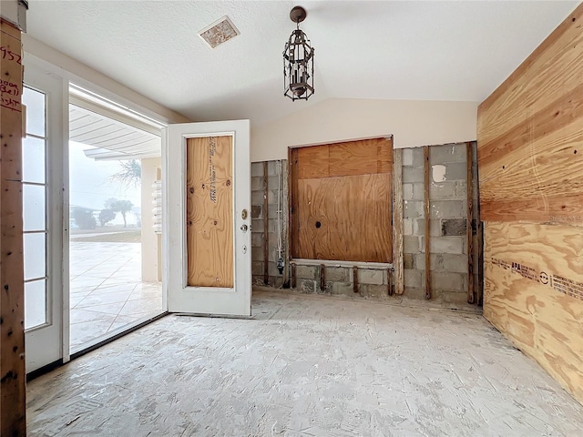 entryway featuring wood walls, a wealth of natural light, and lofted ceiling