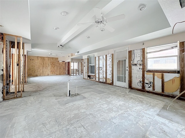 empty room with ceiling fan, wooden walls, beamed ceiling, and a healthy amount of sunlight