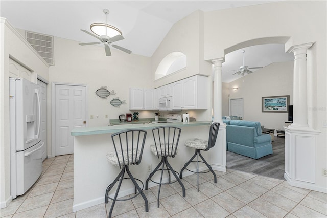 kitchen featuring white appliances, kitchen peninsula, ceiling fan, and ornate columns