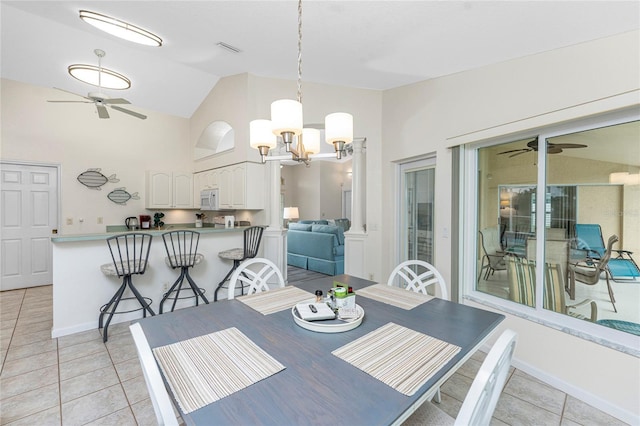 dining room with light tile patterned floors, ceiling fan with notable chandelier, and vaulted ceiling