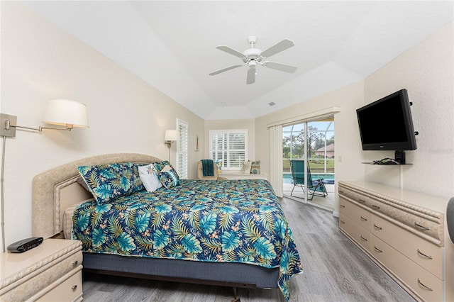 bedroom with a tray ceiling, access to exterior, ceiling fan, and light hardwood / wood-style floors