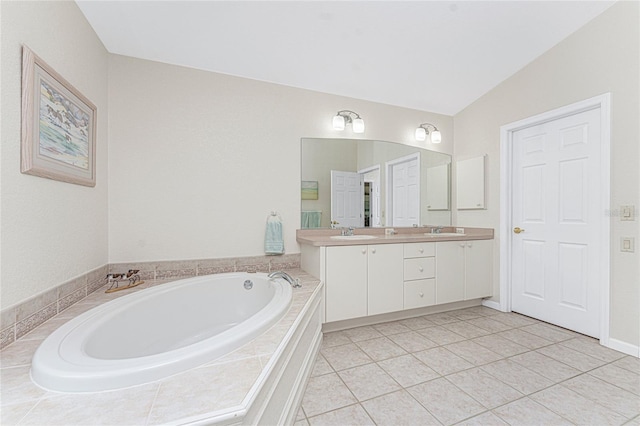 bathroom featuring tile patterned floors, lofted ceiling, tiled bath, and vanity