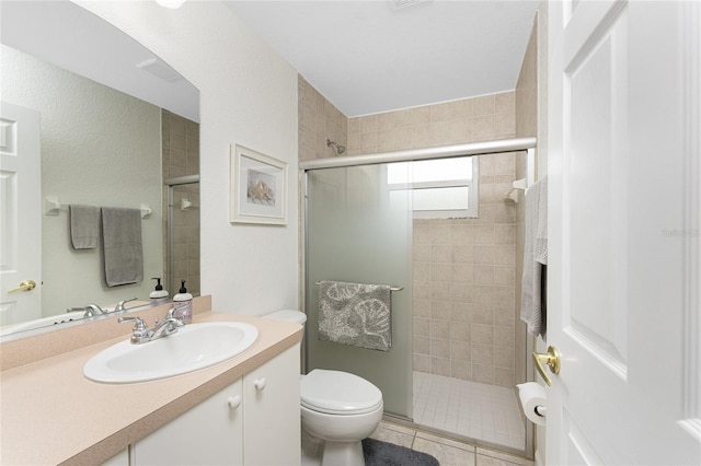 bathroom featuring a shower with door, vanity, tile patterned flooring, and toilet