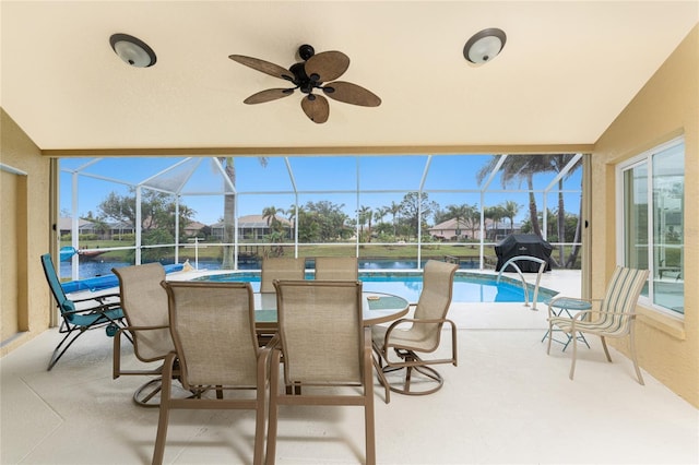 exterior space featuring ceiling fan, a water view, area for grilling, and glass enclosure